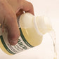 Hand pouring AlliTech_Liquid_Pro bottle onto a white surface