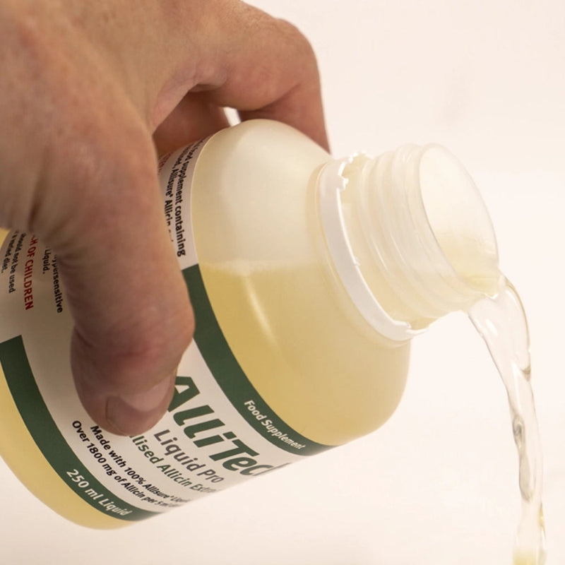 Hand pouring AlliTech_Liquid_Pro bottle onto a white surface