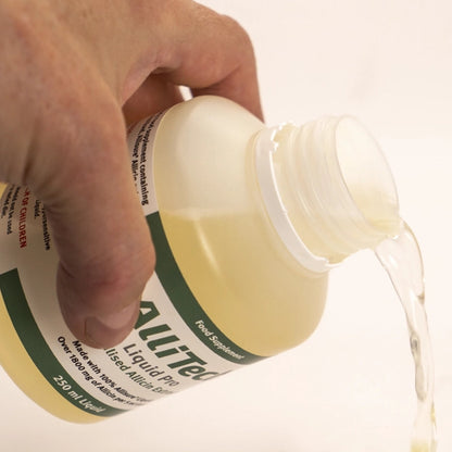 Hand pouring AlliTech_Liquid_Pro bottle onto a white surface