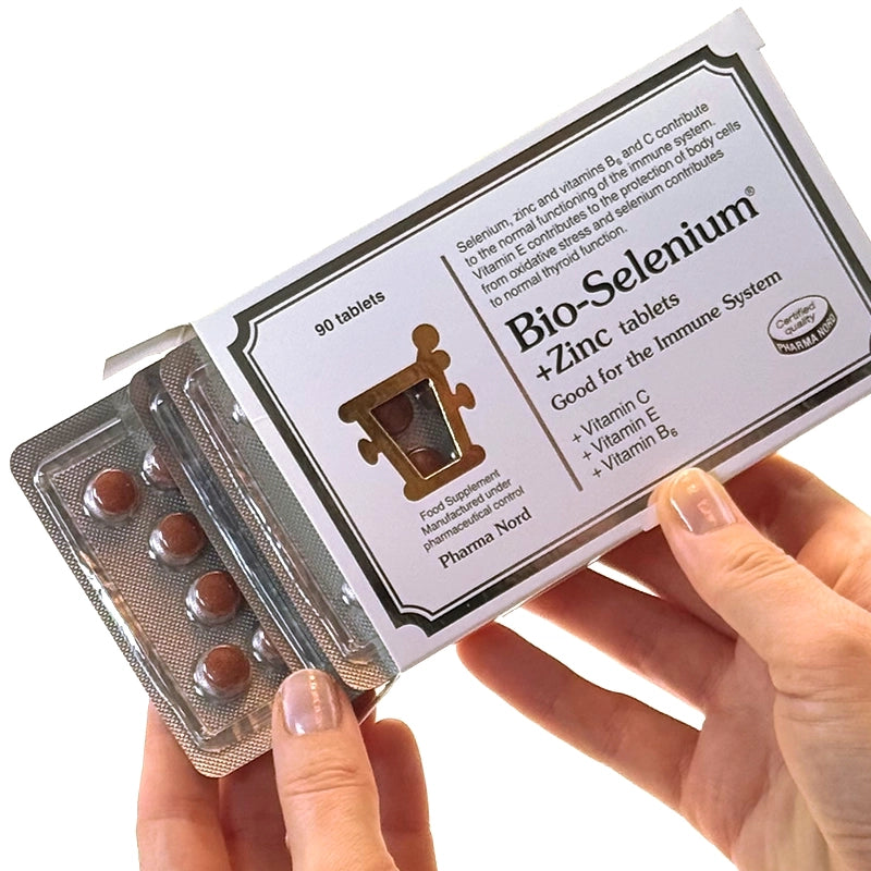 Hand holding a package of Bio-Selenium + Zinc tablets with visible branding.