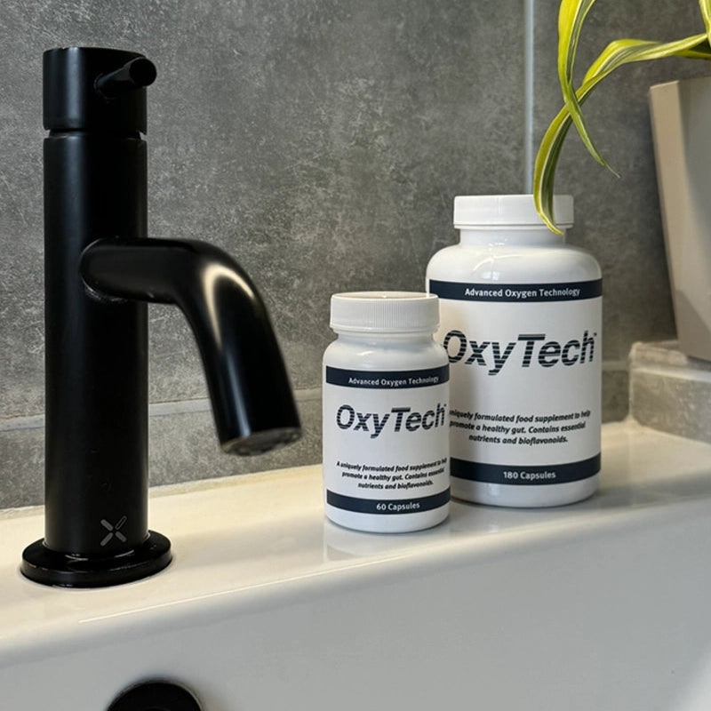Two bottles of OxyTech on a bathroom counter with a black faucet in the background.